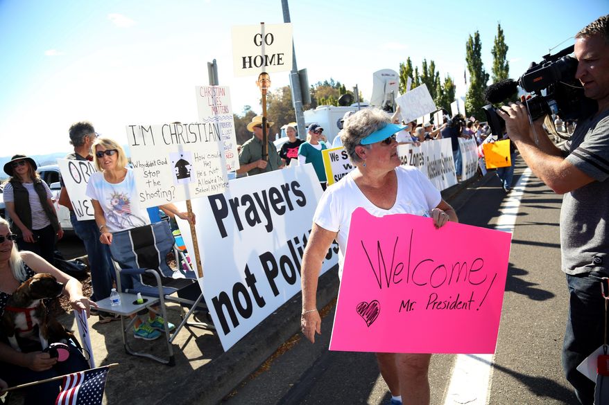 Dulcie Bagley, holds a welcome sign, as she walks by demonstrators outside of Roseburg Regional Airport waiting for President Barack Obama&#39;s arrival in Roseburg, Ore., Friday, Oct. 9, 2015. (AP Photo/Ryan Kang)