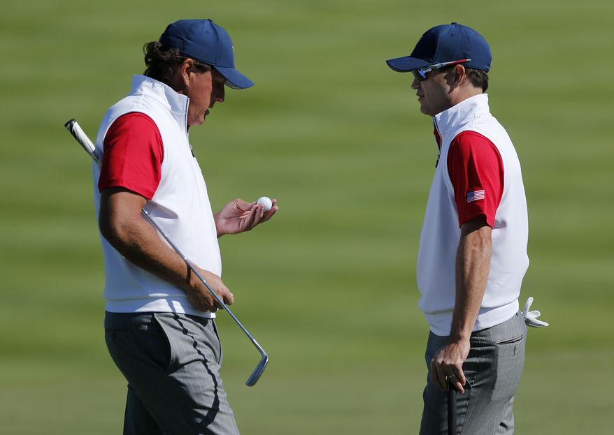 United States' Phil Mickelson, left, and teammate Zach Johnson chat on the second hole during their four ball match at the Presidents Cup golf tournament at the Jack Nicklaus Golf Club Korea, in Incheon, South Korea, Friday, Oct. 9, 2015.(AP Photo/Woohae Cho)