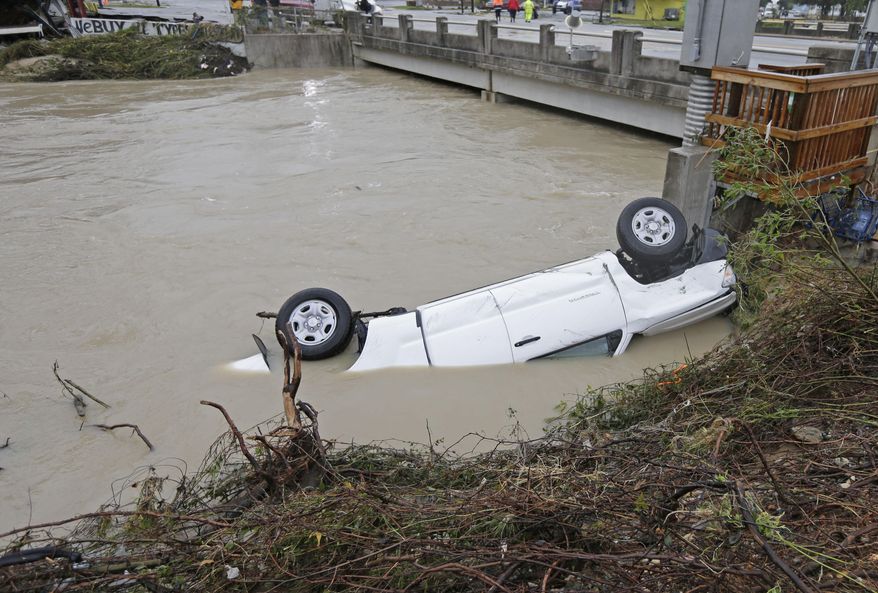 FILE - In this Oct. 5, 2015, file photo, a pickup truck rests against the side of Gills Creek near a bridge in Columbia, S.C. Over the past week, as the water rose after days of unrelenting rain in the heart of South Carolina, the creek spilled misery and pain on rich and poor alike, robbing both of the things most precious to them. (AP Photo/Chuck Burton, File)