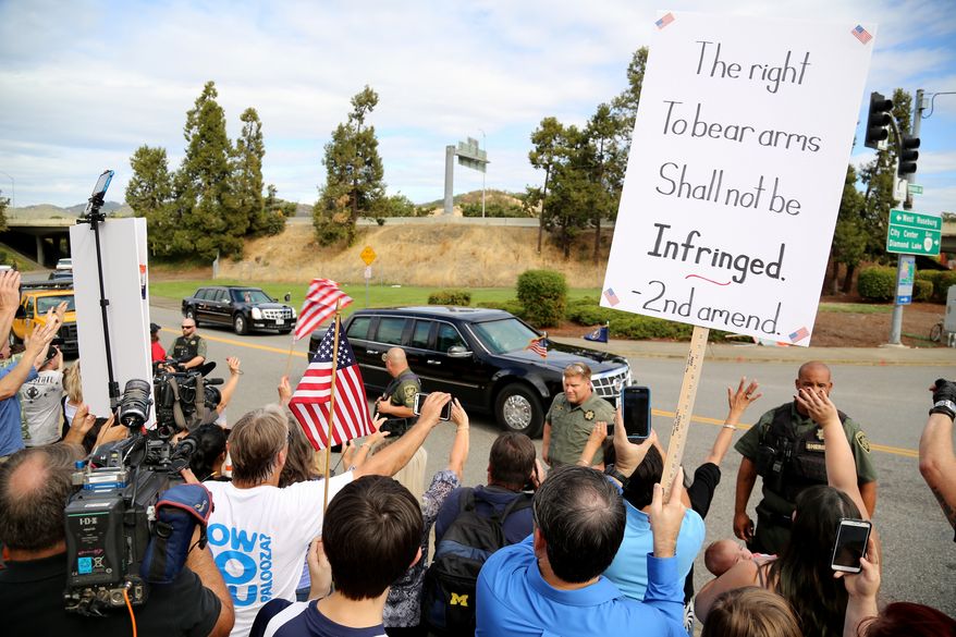 Demonstrators watch as President Barack Obama's motorcade leaves Roseburg High School after a visit with families of victims of the shootings at Umpqua Community College in Roseburg, Ore., Friday, Oct. 9, 2015. The protesters were angry about Obama’s calls for gun restrictions in the wake of the shooting rampage that killed eight students and a teacher at the college. AP Photo/Ryan Kang)
