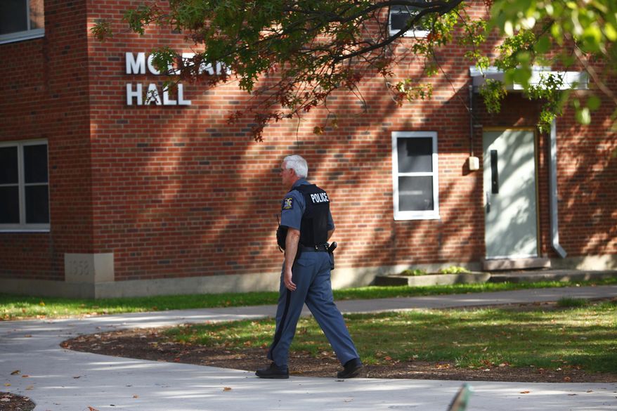 A New York State University police officer walks by McLean Hall at the State University of New York College at Brockport, N.Y., on Sept. 29, 2012. As colleges around the country review their safety plans in the wake of the latest campus shooting in Oregon, officials on New York’s public campuses say training and communication is key. Each campus in the State University of New York system has a full-time, armed police force and every campus is required to have a plan for active shooters. (Associated Press/Democrat & Chronicle, Marie De Jesus) **FILE**