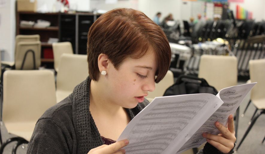 ADVANCE FOR THE WEEKEND OF OCT. 10-11 AND THEREAFTER. - In a Sept. 24, 2015 photo, Kayla Neeley reads sheet music during choir at Humphrey High School. Kayla was born with primary congenital glaucoma, which affects her vision. To read she has to hold the subject just inches from her face. It has not held her back; the 17-year-old senior is a semifinalist for the National Merit Scholarship. (Patrick Murphy/The Norfolk Daily News via AP)  MANDATORY CREDIT