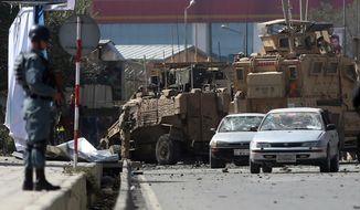 Afghan and foreign soldiers inspect the site of a bomb attack that targeted several armored vehicles belonging to forces attached to the NATO Resolute Support Mission, in downtown of Kabul, Afghanistan, Sunday, Oct. 11, 2015. Gen. Abdul Rahman Rahimi, the Kabul city police chief, said that three Afghan civilians were wounded in the attack that damaged one of the vehicles but caused no fatalities. (AP Photo/Massoud Hossaini)