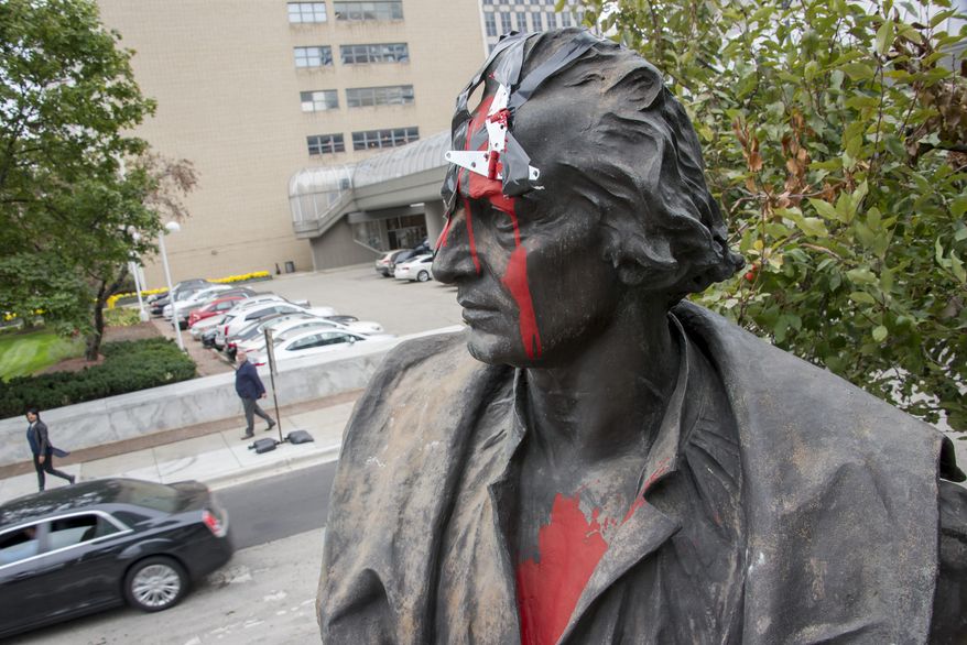 Red paint mars a statue of Christopher Columbus that stands on the corner of East Jefferson and Randolph streets in Detroit on Oct. 12, 2015 in Detroit. The statue was vandalized with a hatchet affixed to the head and red paint. (David Guralnick/Detroit News via AP) DETROIT FREE PRESS OUT; HUFFINGTON POST OUT; MANDATORY CREDIT
