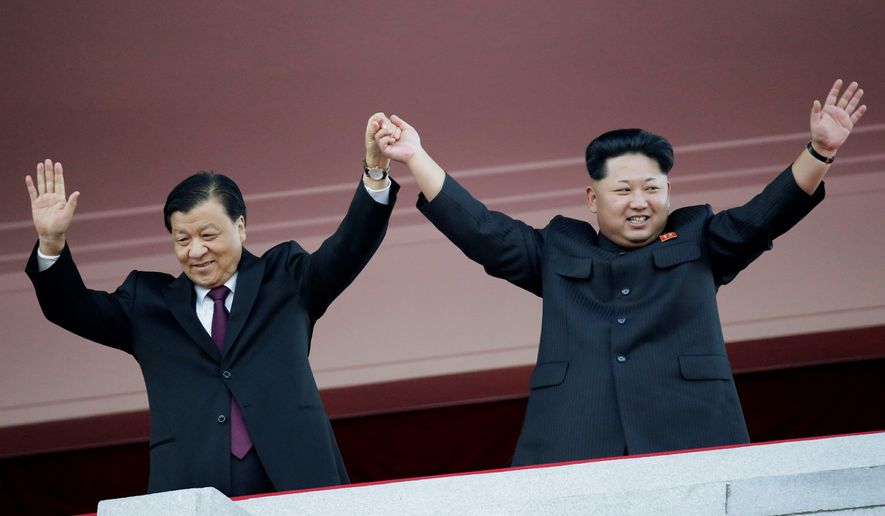 North Korean leader Kim Jong Un (right) waves alongside Chinese official Liu Yunshan during a military parade to mark the 70th anniversary of the North&#39;s ruling party and trumpet Mr. Kim&#39;s third-generation leadership in Pyongyang, North Korea. The two men raised their clasped hands above their heads like a pair of victorious athletes, as international media and tens of thousands of North Koreans looked on. The gesture during a high-profile celebration in Pyongyang seemed designed to scotch appearances that their countries have been drifting apart. (Associated Press)