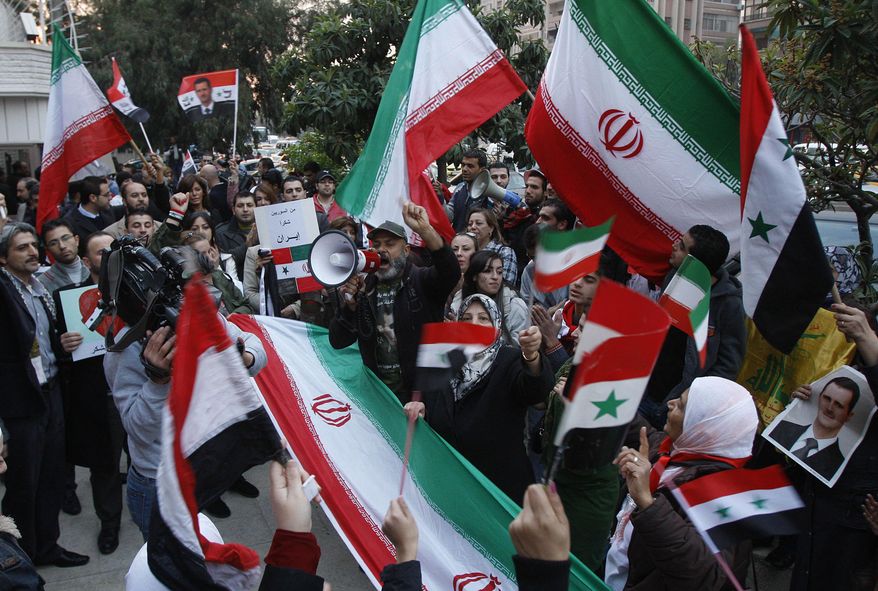 FILE - In this November 24, 2011 file photo, pro-Syrian government protesters shout slogans and wave Iranian and Syrian flags during a protest in front the Iranian Embassy to thank Iran for their support of the Syrian government, in Damascus, Syria. Hundreds of Iranian troops are being deployed in northern and central Syria, dramatically escalating Tehran’s involvement in the civil war as they join allied Hezbollah fighters in an ambitious offensive to wrest key areas from rebels amid Russian airstrikes. (AP Photo/Muzaffar Salman, File)