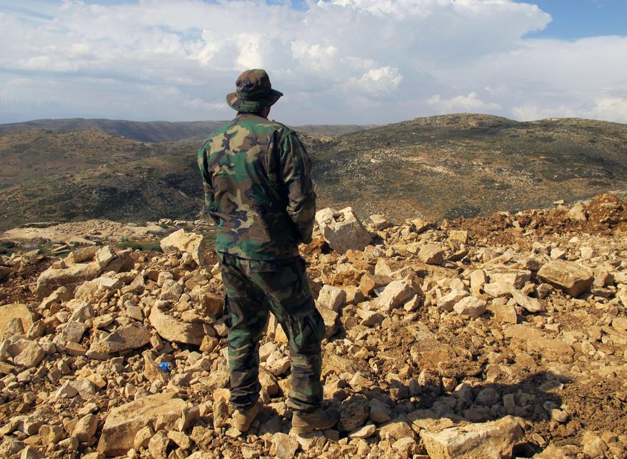 A Hezbollah fighter looks toward Syria from the fields of the Lebanese border village of Brital. Iran is making its greatest progress to date toward its goal of creating a &quot;Shiite Crescent,&quot; a land connection from Iran to Lebanon, where Tehran-backed Hezbollah militants have a long-established political foothold. (Associated Press/File)