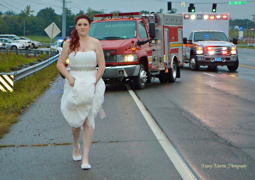 In this Oct. 3, 2015, photo provided by Marcy Martin Photography, her daughter Sarah Ray, in her wedding dress, attends to a car crash in Clarksville, Tenn. Ray's father and grandparents where in a car crash on their way to Ray's wedding reception. Ray, who is a paramedic, went to the scene to check on her relatives. (Marcy Martin Photography via AP)