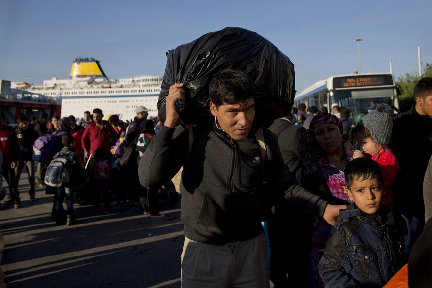 A man carries his belonging upon arriving with his family from the Greek island of Lesbos at the Athens' port of Piraeus Wednesday, Oct. 14, 2015. The international Organization for Migration said more than 593,000 people have crossed this year — of which 453,000 traveled from Turkey to Greece, which has faced a massive influx of people from Syria. (AP Photo/Petros Giannakouris)