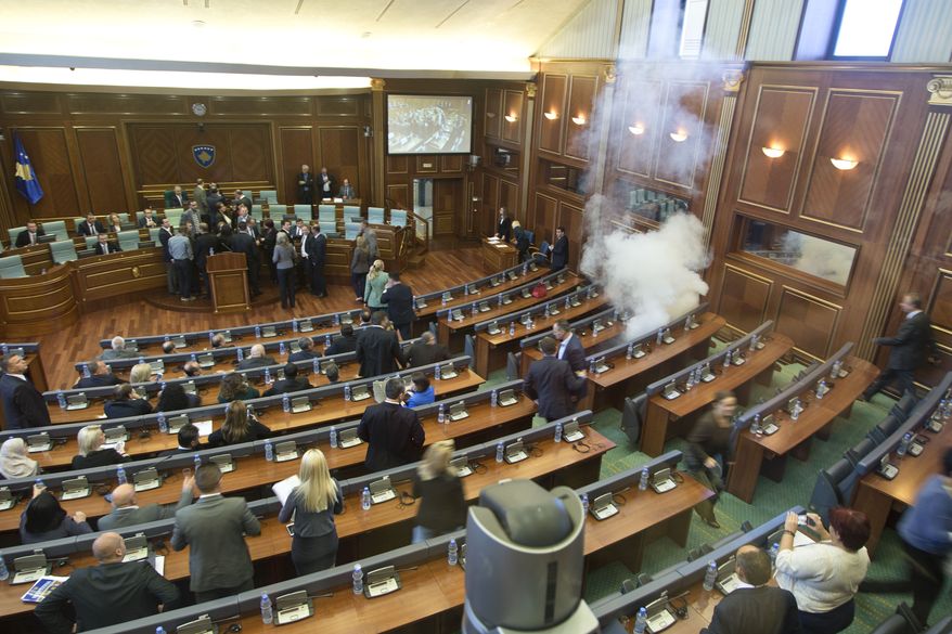 Kosovo lawmakers empty the chamber of Parliament as smoke billows from a tear gas canister thrown by opposition lawmakers in Kosovo disrupting Parliament's session, in the capital Pristina, Thursday, Oct. 15, 2015. The opposition protested over the government's recent EU-sponsored deal with Serbia giving the country's Serb-majority areas greater powers. (AP Photo/Visar Kryeziu)