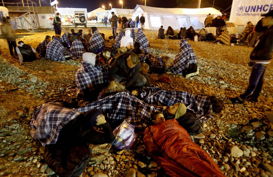 Migrants and refugees, wrapped in blankets, rest on the ground while awaiting a train that will take them towards Serbia, at the transit camp for refugees near the southern Macedonian town of Gevgelija, after crossing the border from Greece, early Friday, Oct. 16, 2015. Thousands of migrants arrive unprepared for cold weather and that affects women and children especially. International Organization for Migration said that more than 600,000 people had arrived by sea into Europe this year and more than 3,000 of them died trying to reach Europe to escape war or poverty. (AP Photo/Boris Grdanoski)