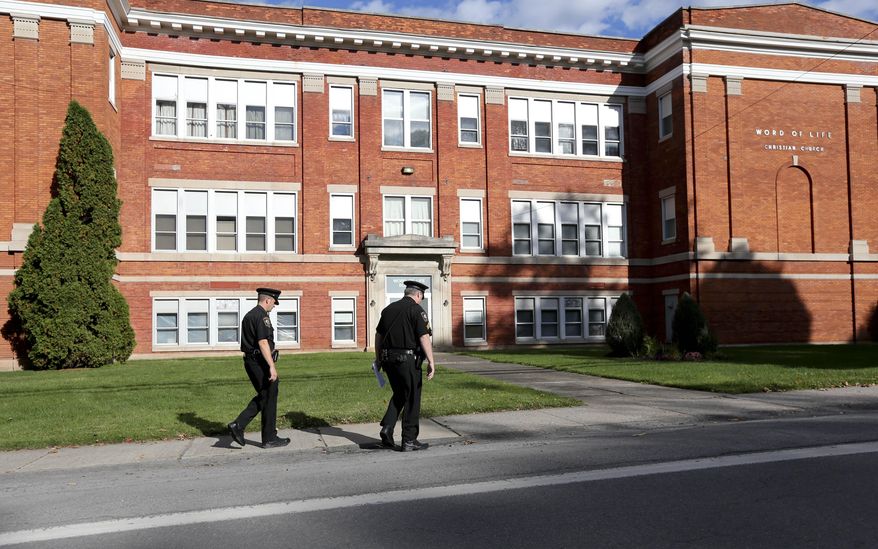 Police walk outside the Word of Life church on Thursday, Oct. 15, 2015, in New Hartford, N.Y. Bruce and Deborah Leonard have been charged in the beating death of their son, Lucas, and the severe beating of his 17-year-old brother, Christopher, inside the church on Sunday. Four other adults were charged with assault in the younger brother's beating, including Sarah Ferguson, 33, the victims' sister. (AP Photo/Mike Groll)