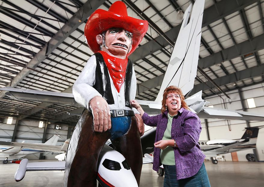 In this photo taken Sept. 29, 2015, Trego-Dugan employee and artist Jean Cook, right, stands next to the Rocket Bob statue she spent months restoring in the Trego-Dugan Maintenance Building at the Central Nebraska Regional Airport in Grand Island, Neb,. Over the years, the statue has welcomed many a visitor to Grand Island at his location near the Trego-Dugan terminal. (Barrett Stinson/The Independent via AP) MANDATORY CREDIT, TV OUT