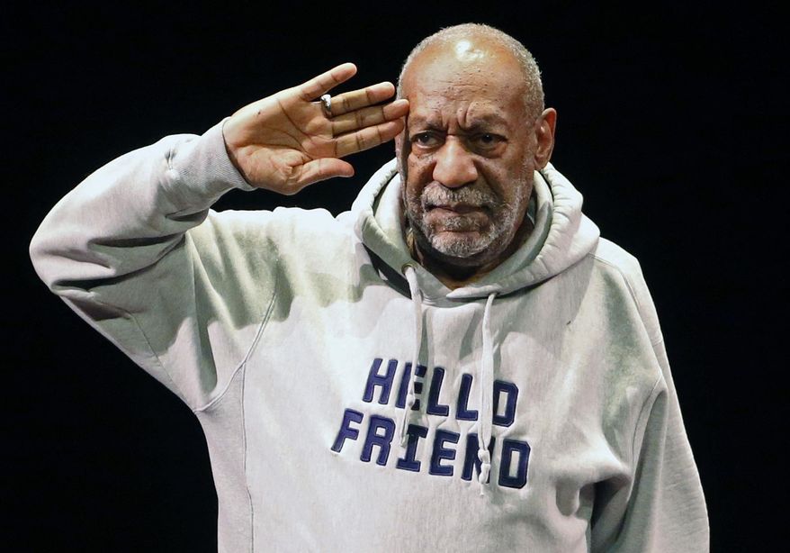 FILE - In this Jan. 17, 2015, file photo, comedian Bill Cosby salutes the crowd as he begins a performance at the Buell Theater in Denver. A year after allegations of sexual assault resurfaced and snowballed, women who’ve accused him of sexual assault are giving emotional interviews en masse, judges are ruling against him and colleges are continuing to revoke honorary degrees bestowed upon him when he was one of the country’s most admired entertainers. (AP Photo/Brennan Linsley, File)