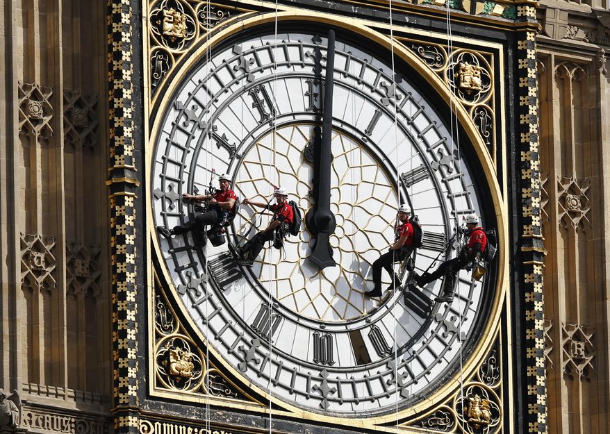 In this file photo dated Monday, Aug. 18, 2014, workers abseil outside the clock face as they clean Big Ben's clock tower of the Houses of Parliament in London. According to reports published Sunday Oct. 18, 2015, the chimes of Big Ben may fall silent for many months as urgent repairs are carried out to the clock and the tower, which must begin as soon as possible.(AP Photo/Sang Tan) ** FILE **