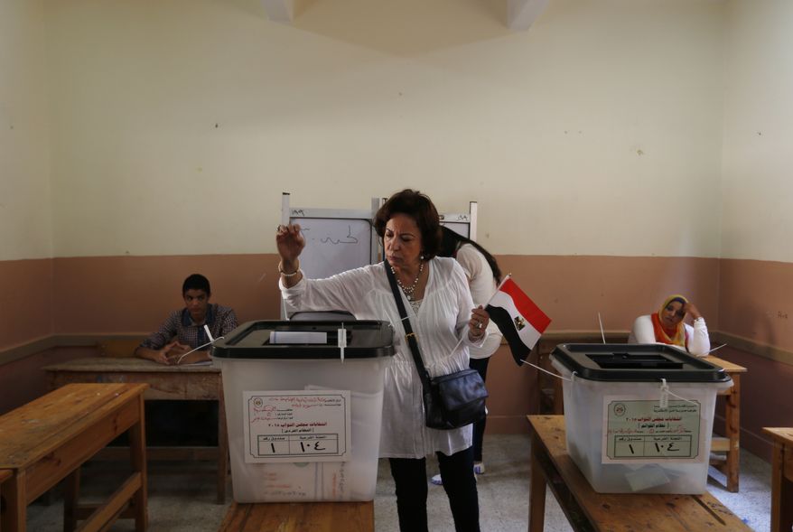 An Egyptian woman holds a national flag as she casts her vote during the first round of Egyptian parliamentary elections, at a polling station in Alexandria, Egypt, Sunday, Oct. 18, 2015. (AP Photo/Hassan Ammar)