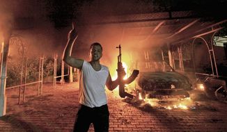 A protester reacts as the U.S. Consulate in Benghazi is seen in flames on September 11, 2012. (Reuters)