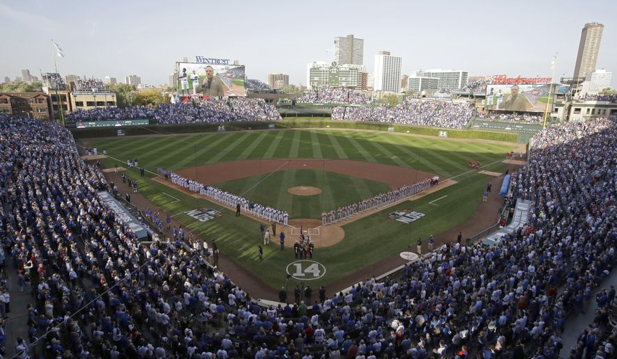 In this Oct. 12, 2015, photo, the Chicago Cubs and St. Louis Cardinals line up on the field at Wrigley Field during the national anthem before Game 3 in baseball's National League Division Series, in Chicago. Wrigley Field is a ballpark that while viewed as a throwback today has in fact played a big role in changing the way fans view sports. It was the first to let them keep foul balls. It was the first with organ music. And it was the first to be cleaned up in an effort to attract women and children. These are just some of many characteristics that sets the fabled stadium apart, along with the famed marquee, the manual scoreboard, the ivy-covered brick outfield walls and the ballhawks in the surrounding streets chasing home runs. (AP Photo/Nam Y. Huh)