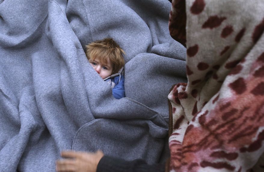 A migrant child is muffled up in blankets while resting on the road near a borderline between Serbia and Croatia, near the village of Berkasovo, Serbia, Tuesday, Oct. 20, 2015. (AP Photo/Darko Vojinovic)