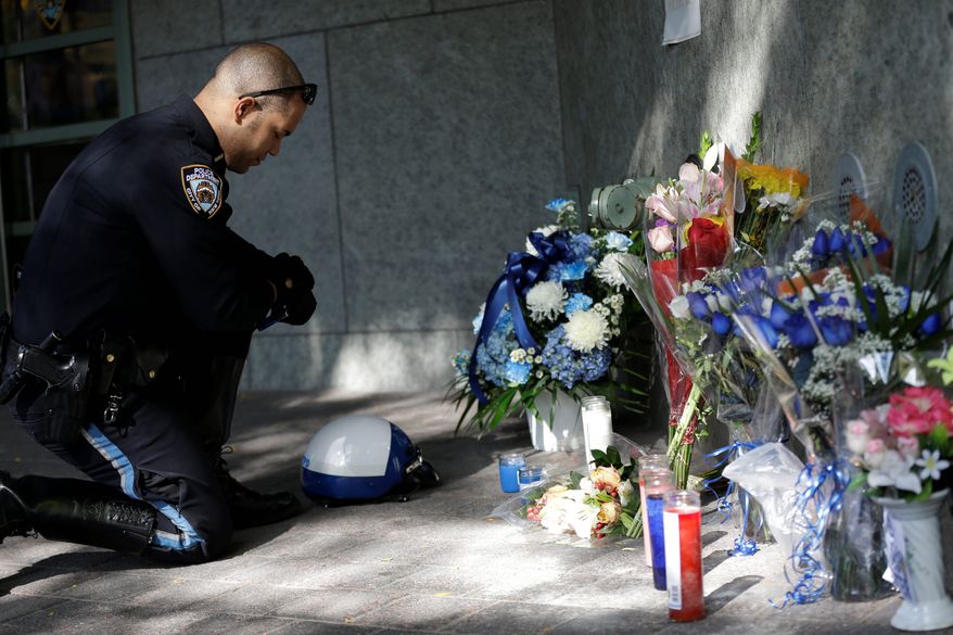 A police officer visits a makeshift memorial to honor New York City Police Department Officer Randolph Holder, who was shot dead Tuesday night during an exchange of gunfire in East Harlem. The man suspected in his slaying had a lengthy rap sheet but was declared eligible for a diversion program. (Associated Press photographs)