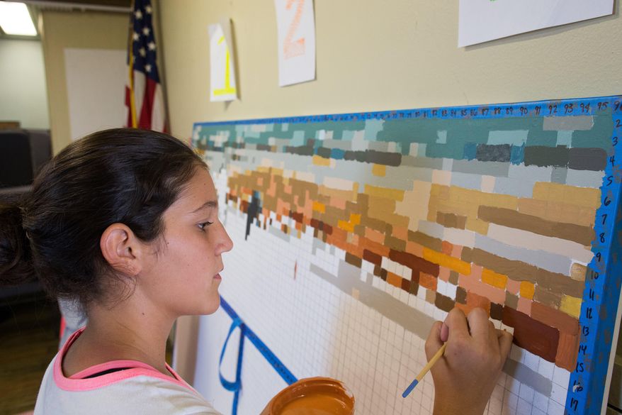 Olivia Martin paints in a square as she helps create a mural at the Malaquite Visitor Center in the Padre Island National Seashore, Tuesday, Oct. 20, 2015 in Padre Island National Seashore, Texas. Using a computer program, which breaks down a painting to square units and assigning each row and column a color and a number, painter Tyler Hudock provided a way for the community to take part in the artistic process. (Courtney Sacco/Corpus Christi Caller-Times via AP) MANDATORY CREDIT; MAGS OUT; TV OUT