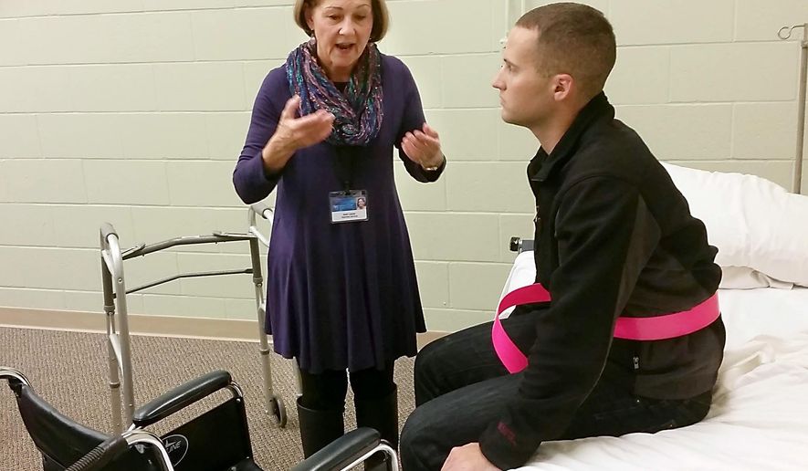 ADVANCE FOR RELEASE MONDAY, OCT. 26, 2015, AT 12:01 A.M. CDT. AND THEREAFTER - In this Oct. 14, 2015 photo, hospice volunteer Joan Lucas, left, explains how to help a patient up from a bed and into a wheelchair in Mankato, Minn. Jon Kearney, attending a training session offered by Mayo Clinic Health System&#39;s hospice program, waits to help her demonstrate the technique. (Pat Christman/The Free Press via AP) MANDATORY CREDIT