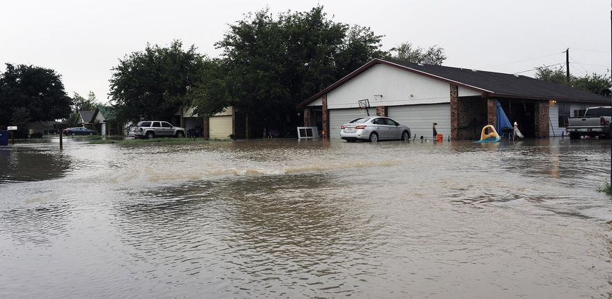 Water flows into a neighborhood Thursday, Oct. 22, 2015, in Midland County, Texas following heavy rains overnight. One home owner said he had water in his garage and his neighbor had water in his house. (Mark Sterkel/Odessa American via AP)
