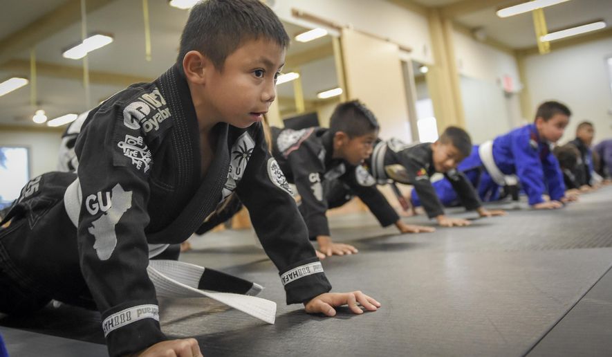 ADVANCE FOR WEEKEND EDITIONS, OCT. 24-25 - In this photo taken Oct. 13, 2015, students warm up before class with drills at the Figo/Bonsai Academy Guam in the International Sports Center in Anigua, Guam. Mixed martial artists at the top of their game often speak about how they dedicate their lives to two things: their loved ones and their passion for the arts. Twin brothers Elijah and Luis Reyes are no different. It was the Mangilao residents' hard work and diligence that has contributed to the success of their school. (Mark Scott/Pacific Daily News via AP) ALL GUAM, MICRONESIA MEDIA OUT, MANDATORY CREDIT