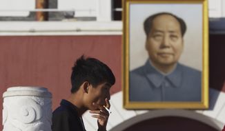 A man smokes near a portrait of late Chinese leader Mao Zedong hung on a replica of the Tiananmen Gate in Yinchuan in northwestern China&#39;s Ningxia Hui autonomous region on Thursday, Oct. 8, 2015.  Research published in the medical journal The Lancet says one in three of all the young men in China are likely to die from tobacco, but that the number can fall if the men quit smoking. (AP Photo/Ng Han Guan)