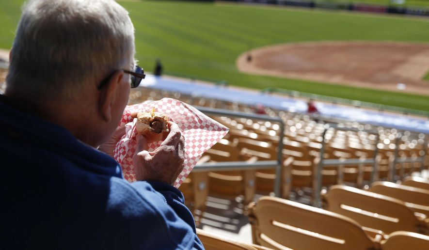 FILE - In this March 4, 2015 file photo, a fan eats a hot dog before a spring training exhibition baseball game between the Chicago White Sox and the Los Angeles Dodgers, in Phoenix. On the eve of the World Series, where hot dogs are a staple in the stands, the World Health Organization on Monday, Oct. 26, 2015 labeled the all-American wiener, bacon and other processed meats as being "carcinogenic to humans." (AP Photo/John Locher, File)