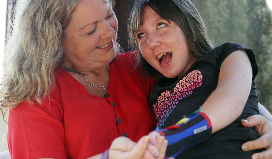 In this Aug. 7, 2015 photo, New Zealander Jenn Hooper holds her daughter Charley, 10, in Bali, Indonesia. As their girl's body grew bigger, her parents feared her world would grow smaller - how would they lift her or get her out of the house? So Jenn and Mark Hooper came up with a radical solution. They gave their daughter hormones to stop her growth. Charley is now around 1.3 meters tall (4 feet 3 inches) and 24 kilograms (53 pounds), and will remain so for the rest of her life. (AP Photo/Firdia Lisnawati)
