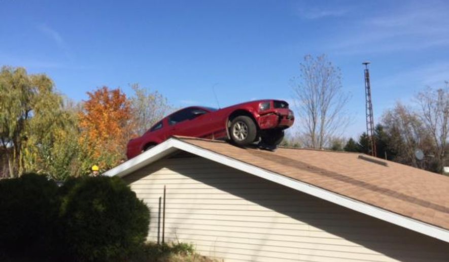 In this Oct. 26, 2015 photo provided by the Michigan State Police, a Ford Mustang is stopped on a roof of a house in Woodhull Township, Mich. State police say the driver had a medical problem and lost control of his car on Interstate 69 in Shiawassee County. (Michigan State Police via AP)