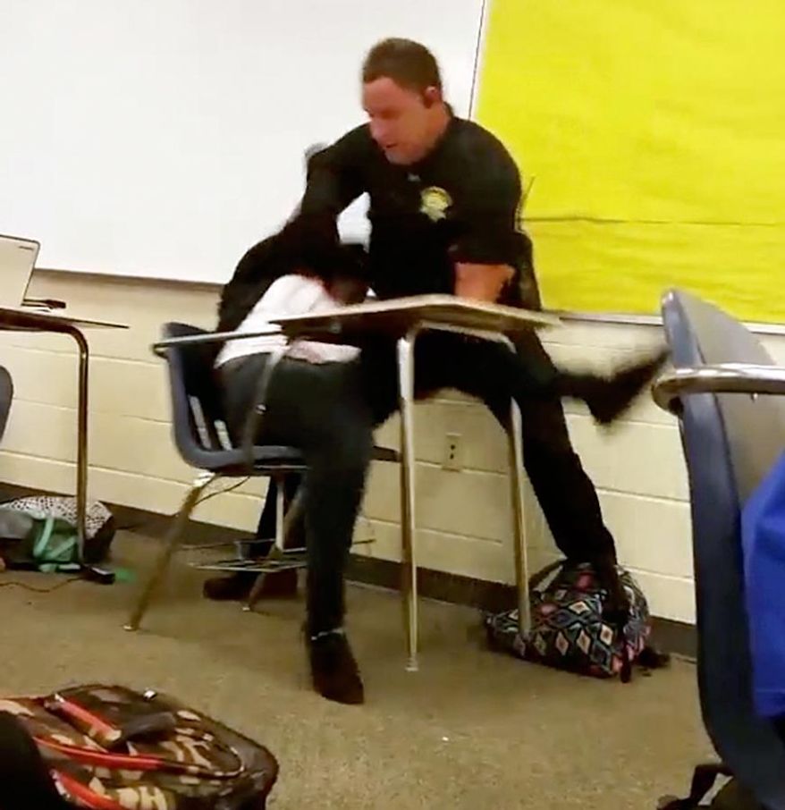 In this Monday, Oct, 26, 2015, photo made from video taken by a Spring Valley High School student, Senior Deputy Ben Fields tries to forcibly remove a student who refused to leave her high school math class, in Columbia S.C. The Justice Department opened a civil rights investigation Tuesday after Fields flipped the student backward in her desk and tossed her across the floor. (Associated Press)