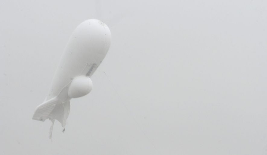 An unmanned 240-foot helium-filled Army surveillance blimp floats through the air while dragging a tether line just north of Exchange, Pennsylvania on Wednesday.  The blimp detached from its station at the military&#x27;s Aberdeen Proving Ground in Maryland. (Associated Press)