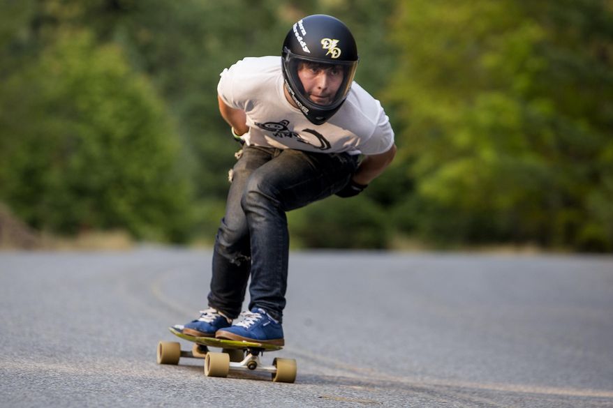 ADVANCE FOR SATURDAY, OCT. 31, 2015- In this photo taken on Aug. 20, 2015, Chris Burton races down Fernan Lake Road on a specially designed skateboard at speeds topping 40 miles per hour, in Coeur d'Alene, Idaho. (Jake Parrish /Coeur D'Alene Press via AP) MANDATORY CREDIT