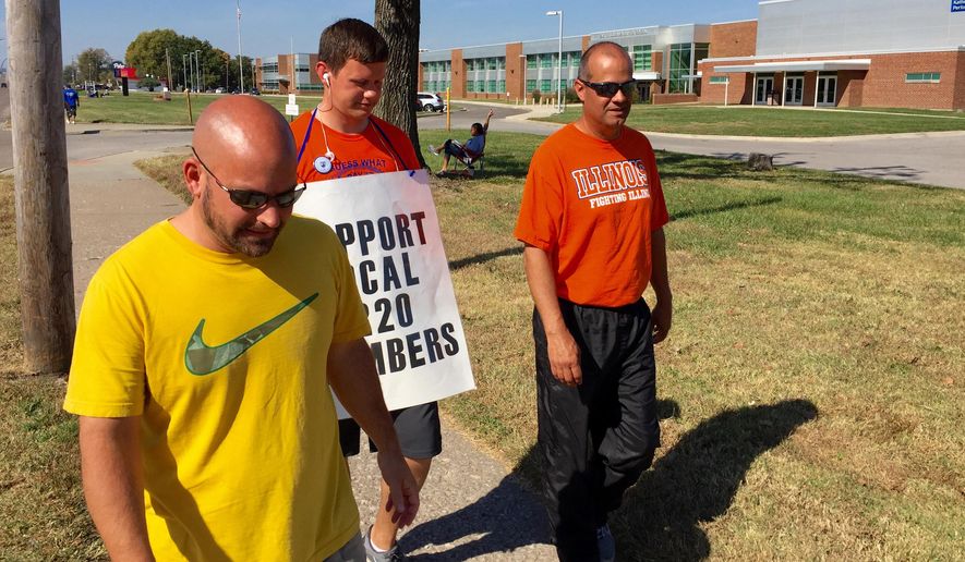 Striking East St. Louis teachers, from left, Jeff Schneider, Josh Cummins and Paul Thies, continue to walk the picket line in front of East St. Louis Senior High School Tuesday, Oct. 27, 2015 in East St. Louis, Ill. The strike began Oct. 1 after union members rejected a tentative deal between their representatives and the school district in East St. Louis, an impoverished black community of about 27,000 residents in southwestern Illinois that is across the Mississippi River from St. Louis. Some students and their families aren’t waiting for a resolution, instead opting to move or transfer to other districts. (Steve Nagy/Belleville News-Democrat, via AP)