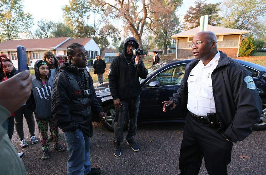 Interim Ferguson, Mo., Police Chief Andre Anderson, right, talks with people Wednesday Oct. 28, 2015, outside the crime scene tape on the 7700 block of Paddington Dr., in Normandy, Mo. Authorities say a St. Louis-area officer who exchanged gunfire with an 18-year-old suspect never hit him, even as the suspect’s father questioned police claims that the suspect killed himself. Amonderez Green of Florissant died early Thursday, 14 hours after a confrontation with a Normandy officer. (Chris Lee/St. Louis Post-Dispatch via AP)