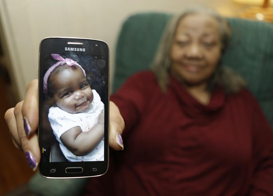 In this Wednesday, Oct. 28, 2015, photo, Beatrice Wakefield holds up a picture of her granddaughter Aavielle at her home in Cleveland. Wakefield was in a car with her daughter-in-law, her granddaughter Aavielle Wakefield and another child on the way to the grocery store when someone began firing at the vehicle, striking it numerous times. Aavielle, 5-months-old, sitting in her car seat, was fatally struck in the torso. No one else was injured. The killing remains unsolved. (AP Photo/Tony Dejak)