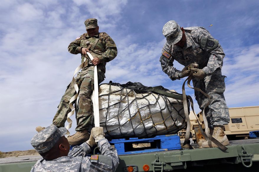 Sgt. 1st Class Terrill Lee, from left, Sgt. James Ray and Staff Sgt. Noe Amador, secure the remains of a Pentaceratops, Thursday, Oct. 29, 2015, in the Bisti-De-Na-Zin Wilderness area south of Farmington, N.M. The fossils are encapsulated in heavy plaster jackets. They're being trucked to the New Mexico Museum of Natural History and Science in Albuquerque. (Jon Austria/The Daily Times via AP) MANDATORY CREDIT