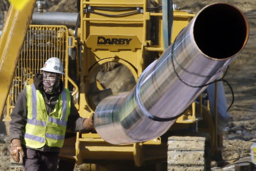 ADVANCE FOR SATURDAY, OCT. 31, 2015 - FILE - In this Feb. 13, 2015, file photo, a worker shields his face against temperatures in the teens as he guides a section of pipe while working on a shale gas pipe line in Zelienople, Pa. Tens of thousands of miles of pipeline are proposed for Pennsylvania during the next 10 years, according to state officials, and while the last decade of oil and gas development primarily took place in the state's shale regions, the next phase will tunnel through the midstate. (AP Photo/Keith Srakocic, File)