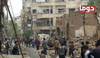 In this photo provided by the Syrian anti-government activist group Douma Revolution, which has been authenticated based on its contents and other AP reporting, people gather near damaged buildings, in the aftermath of an airstrike that activists said was carried out by Russia, in Douma, Syria, Thursday, Oct. 29, 2015. (Douma Revolution via AP)
