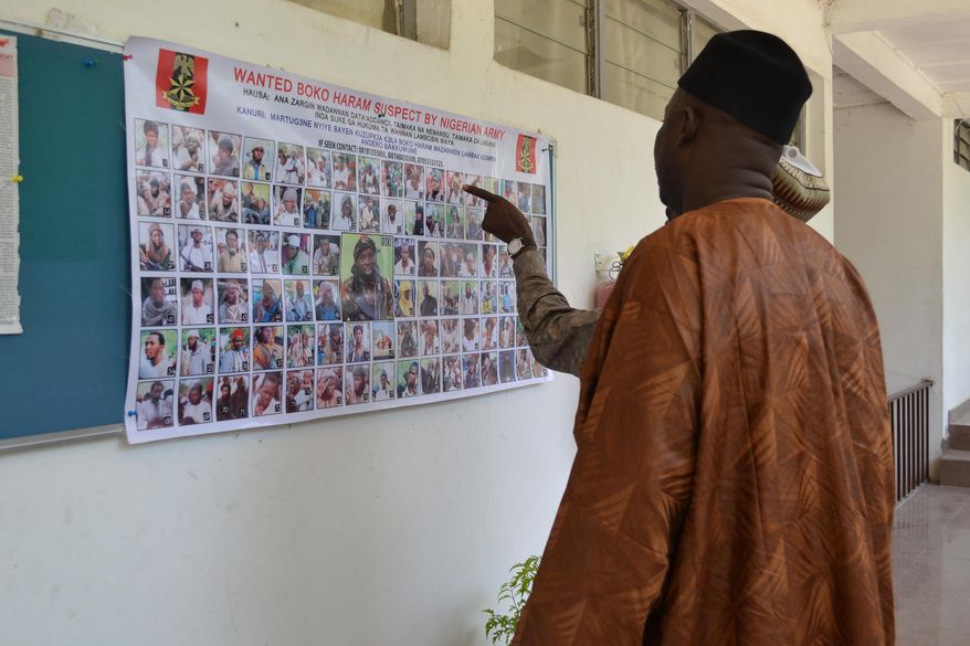 In this photo taken Friday, Oct. 30, 2015, people look at a poster featuring photos of wanted Boko Haram members, pasted onto the wall by Nigeria army in Maiduguri, Nigeria. Nigeria's army has displayed the poster of 100 photographs of the most wanted Boko Haram militants including the shadowy leader whom they claim to have killed on at least three occasions. (AP Photo/Jossy ola)