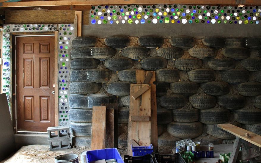 ADVANCE FOR SUNDAY, NOV. 1 AND THEREAFTER - In this photo taken Sept. 25 2015, shows some of the recycled materials at Rob Barbor’s home in Buckannon, W.Va. Reused materials like glass bottles and used automobile tires serve as the primary building block for Rob Barbor’s rammed earth solar passive home in Upshur County. It took him two and a half years to set the tire bricks that make up multiple exterior and interior walls in his home. (Anna Patrick/Gazette Mail via AP)