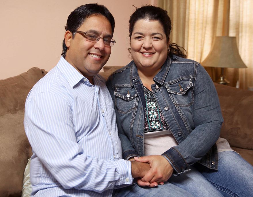 ADVANCE FOR USE SUNDAY, NOV. 1 - In this photo taken Sept. 19, 2015, Esperanza Sosa Valdes and Ariel Del Sol Perez hold hands together as they pose in the living room of their home in Hastings, Neb. The couple navigated, negotiated, perspired and bribed their way along the perilous, 3,300-mile trek from Ecuador to the United States in the fall of 2012. It was a successful journey that landed them in Central Nebraska with enough stories to fill several books. (Andrew Carpenean/The Independent via AP) MANDATORY CREDIT