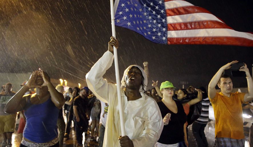 Protesters march to mark the one-year anniversary of Michael Brown being shot and killed by Ferguson Police Officer Darren Wilson, in this Aug. 9, 2015, file photo. Years before the high-profile deaths of Brown, Trayvon Martin and Freddie Gray, more than half of African-American millennials indicated they, or someone they knew, had been victimized by violence or harassment from law enforcement, a report released Wednesday, Nov. 4, 2015, says. (AP Photo/Jeff Roberson, File)