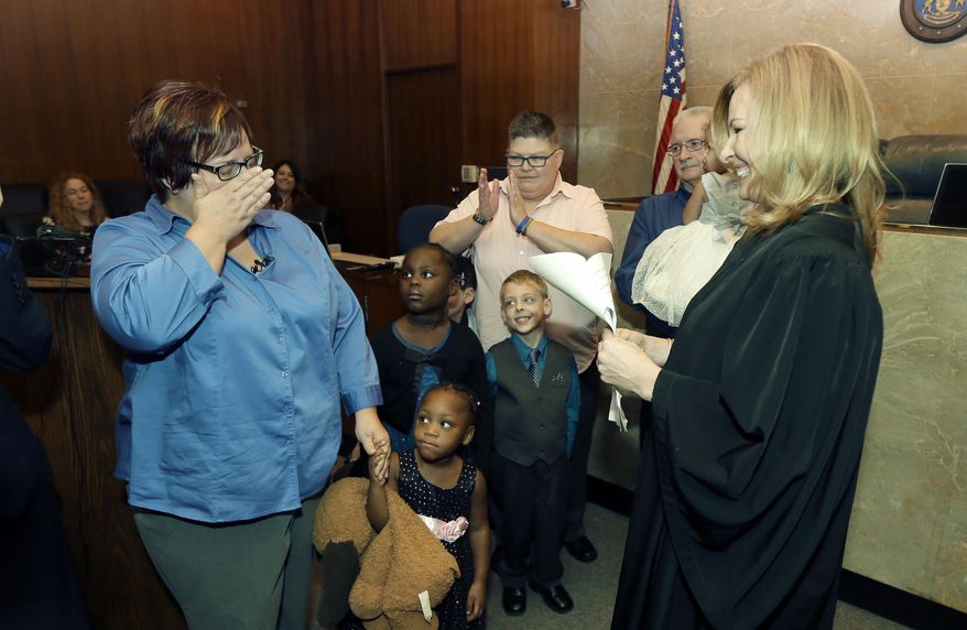 In this file photo from 2015, April DeBoer, left, wipes away tears before Judge Karen McDonald, right, and DeBoer's spouse Jayne Rowse, center, after an adoption ceremony at the Oakland County Circuit Court, Thursday, Nov. 5, 2015, in Pontiac, Mich. A bill in the Tennessee state legislature would allow faith-based orphanages and child-placement organizations to decline adoptions or foster care based on religious beliefs, including opposition to LGBT parents. (AP Photo/Carlos Osorio) **FILE**
