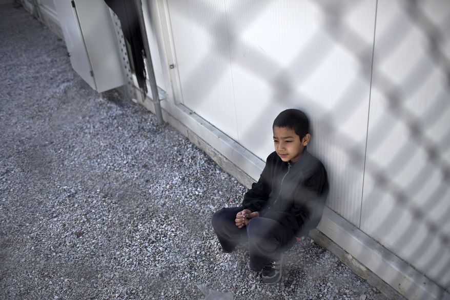 A boy sits inside an enclosure at the migrant and refugee registration camp in Moria, on the island of Lesbos, Greece, Thursday, Nov. 5, 2015. The European Union predict that around 3 million more migrants are expected to arrive in the 28-nation bloc by the end of next year. (AP Photo/Marko Drobnjakovic)