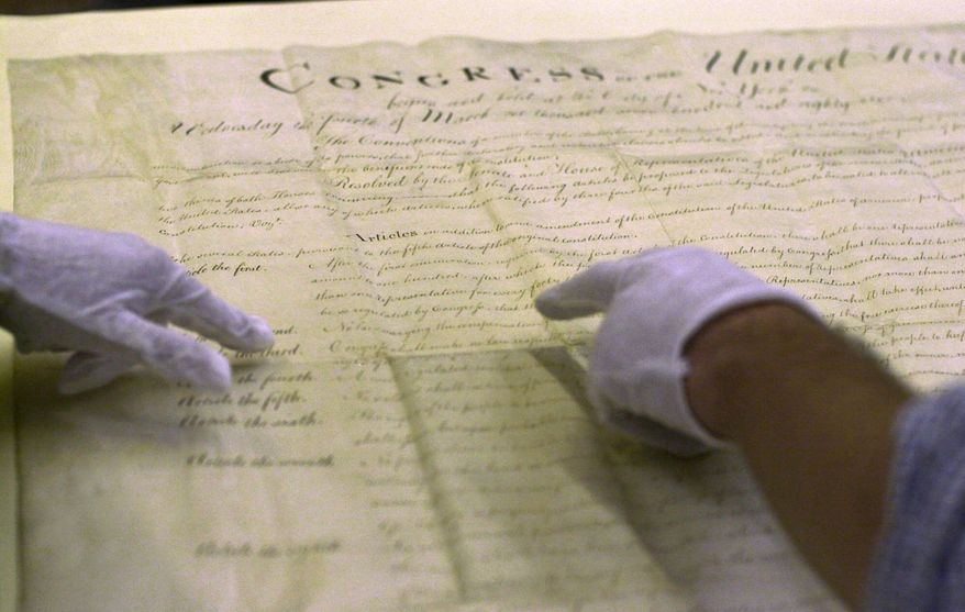 Workers at the Massachusetts State Archives in Boston point to a section of an original copy of the Bill of Rights sent to Massaschusetts by President Washington for ratification. Massachusetts did not ratify the Bill of Rights until the 1930s, preferring the state's own Declaration of Rights written by John Adams. (Associated Press)