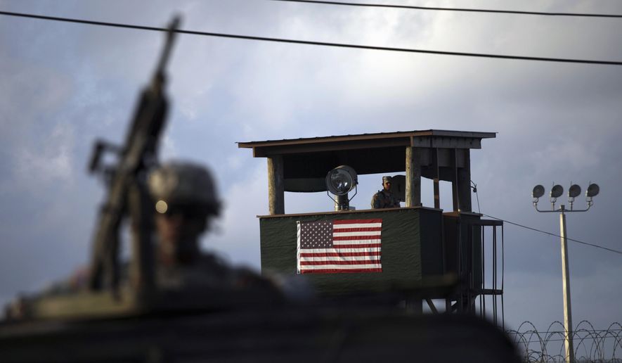 A U.S. trooper mans a machine gun in the turret on a vehicle as a guard looks out from a tower in front of the detention facility at Guantanamo Bay U.S. Naval Base, Cuba, in this March 30, 2010, file photo. (AP Photo/Brennan Linsley, File)