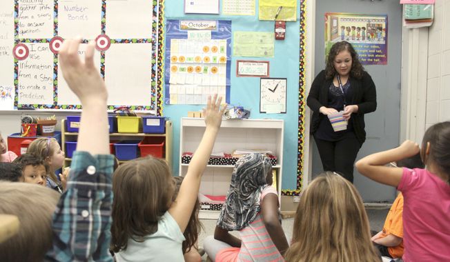 A student teacher in the second-grade classroom of teacher Susanne Diaz at Marcus Whitman Elementary School, goes over lessons with students, in Richland, Wash. (Ty Beaver/The Tri-City Herald via AP) ** FILE ** 